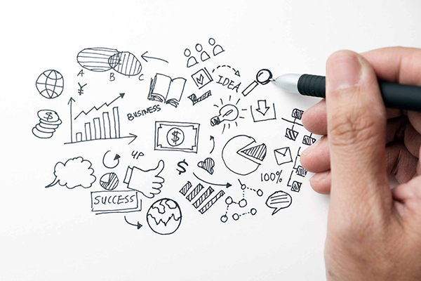 Hand holding pen over page with small drawings